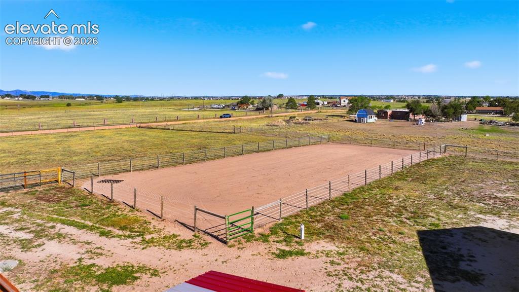 Image 7 of 50: Fenced outdoor arena with a sand base, surrounded by expansive open fields
