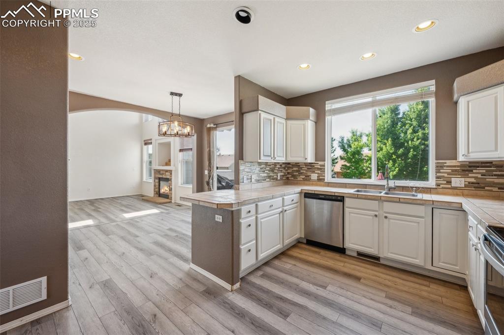 Image 13 of 38: Kitchen featuring white cabinets, decorative backsplash, a peninsula, stain