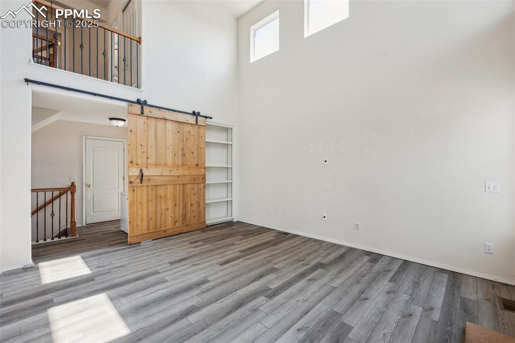 Image 19 of 38: Unfurnished living room featuring a towering ceiling, wood finished floors,