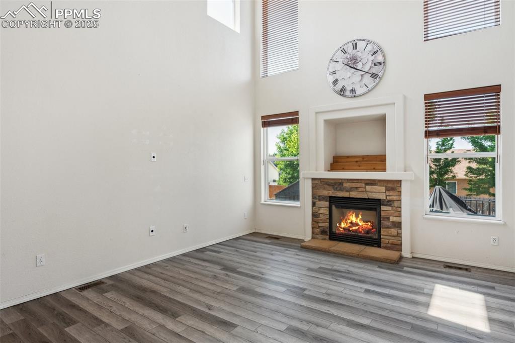 Image 20 of 38: Unfurnished living room featuring wood finished floors, a stone fireplace,