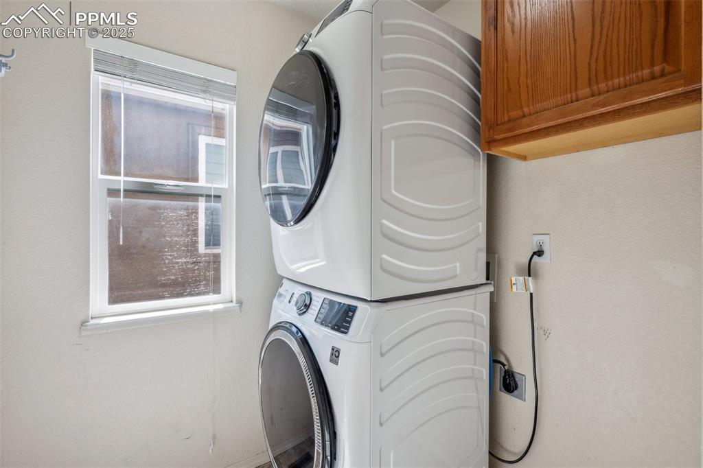 Image 22 of 38: Laundry room featuring cabinet space and stacked washer and clothes dryer