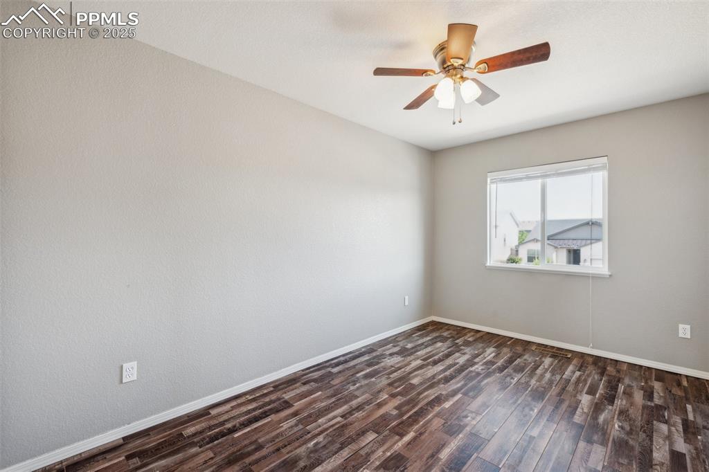 Image 23 of 38: Empty room with dark wood finished floors and ceiling fan