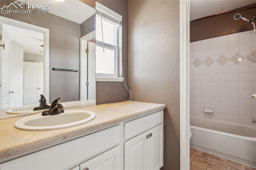 Image 25 of 38: Full bath featuring vanity, a textured wall, and shower / bath combination