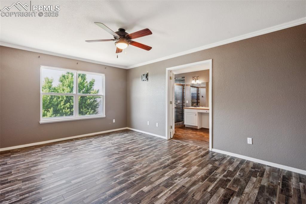 Image 28 of 38: Unfurnished room featuring a ceiling fan, dark wood-style flooring, crown m