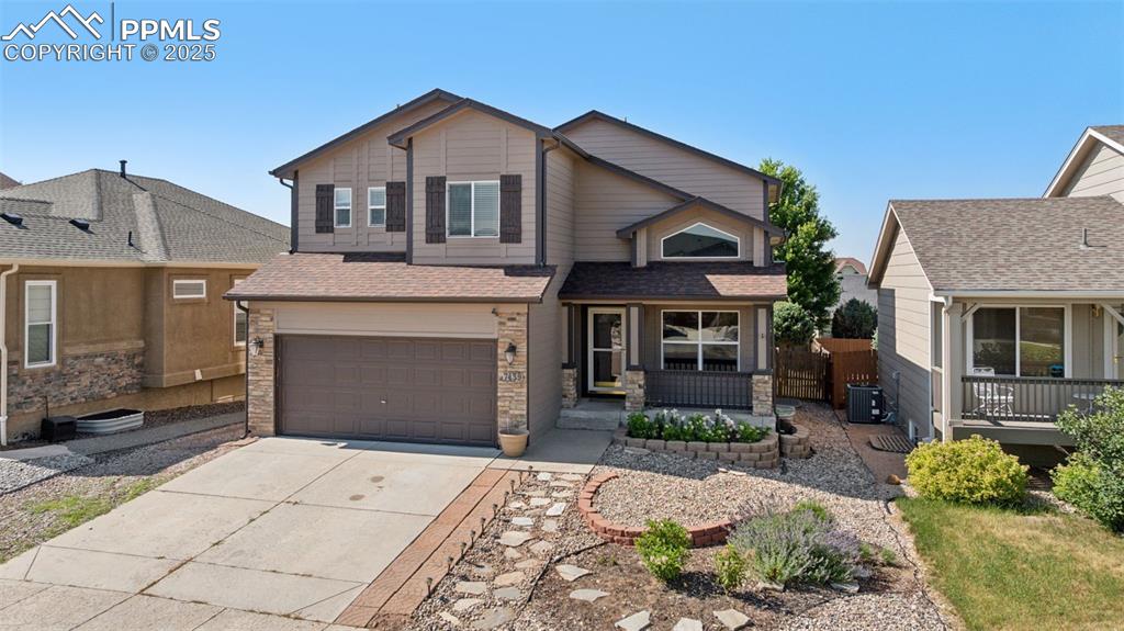 Image 3 of 38: View of front of home featuring concrete driveway, stone siding, a garage,