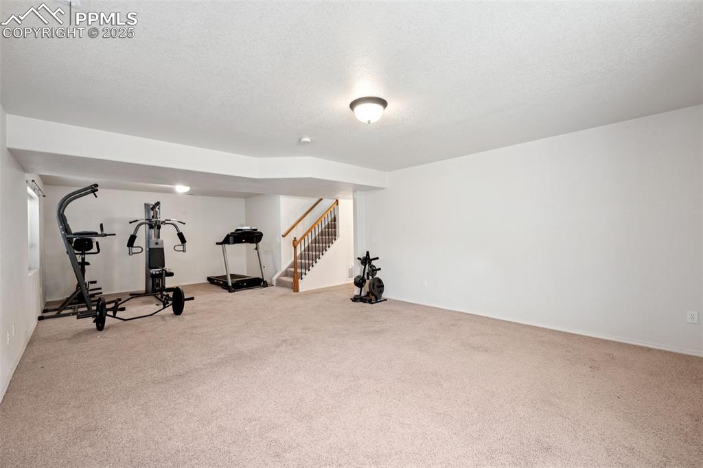 Image 35 of 38: Exercise room with light colored carpet and a textured ceiling