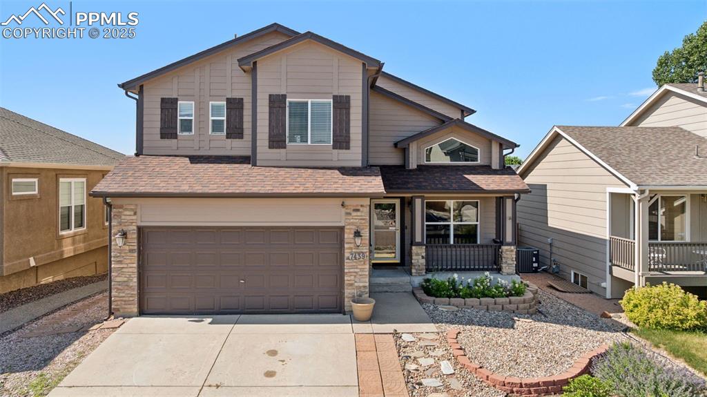 Image 8 of 38: View of front of house with a porch, stone siding, concrete driveway, roof