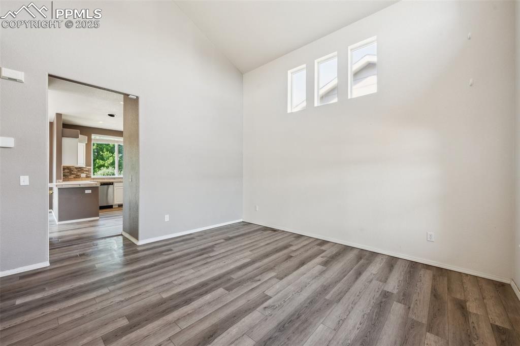 Image 9 of 38: Unfurnished room featuring wood finished floors and high vaulted ceiling