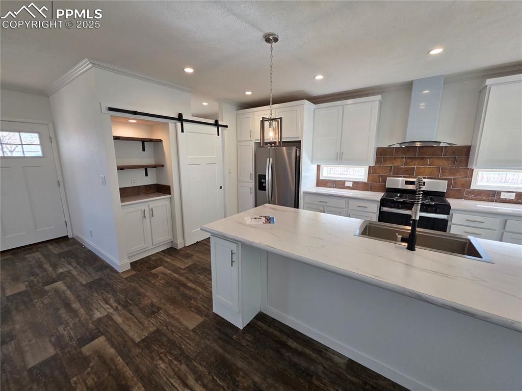Image 10 of 25: Kitchen with white cabinets, stainless steel appliances, a barn door, wall