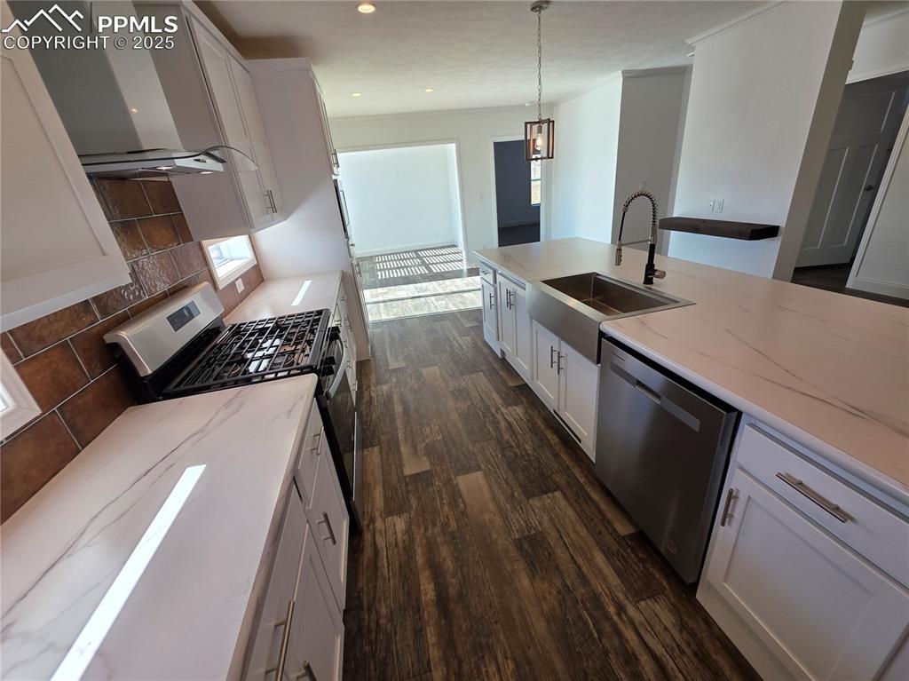 Image 14 of 25: Kitchen with white cabinetry, pendant lighting, stainless steel appliances,