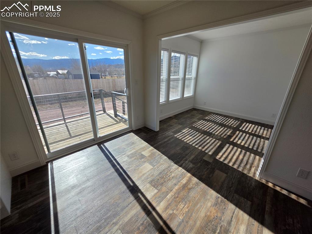 Image 15 of 25: Spare room with dark wood-type flooring, crown molding, and a mountain view