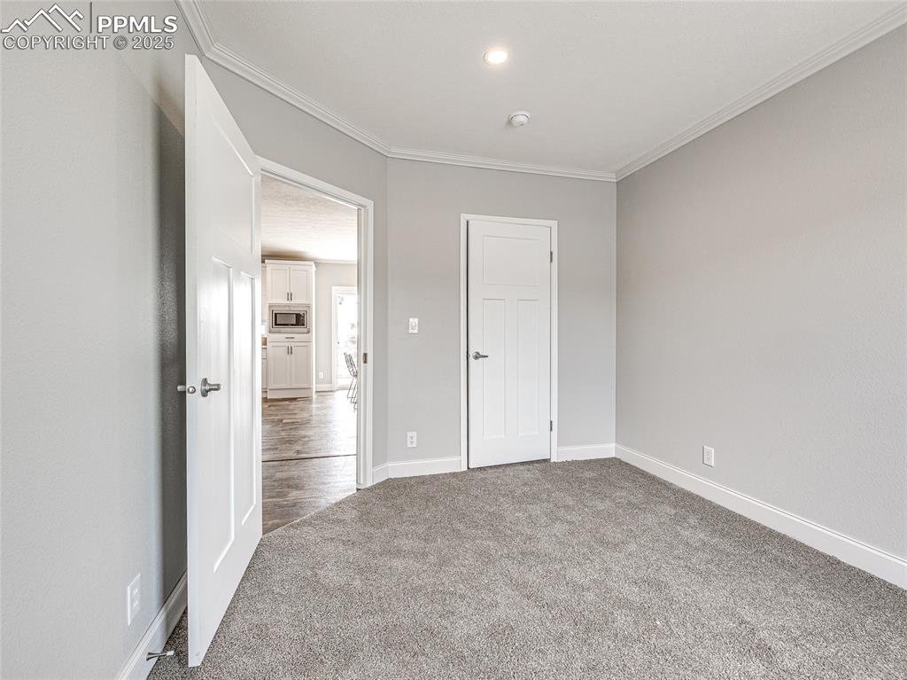 Image 17 of 25: Unfurnished bedroom featuring ornamental molding, light carpet, a closet, a