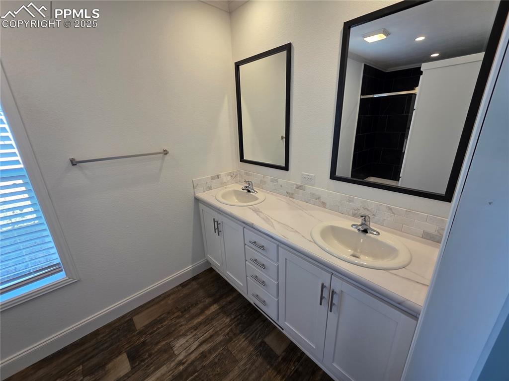 Image 24 of 25: Bathroom featuring double vanity, a stall shower, dark wood-type flooring,