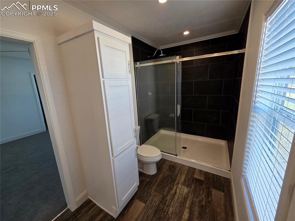 Image 25 of 25: Full bath with a stall shower, dark wood finished floors, crown molding, an