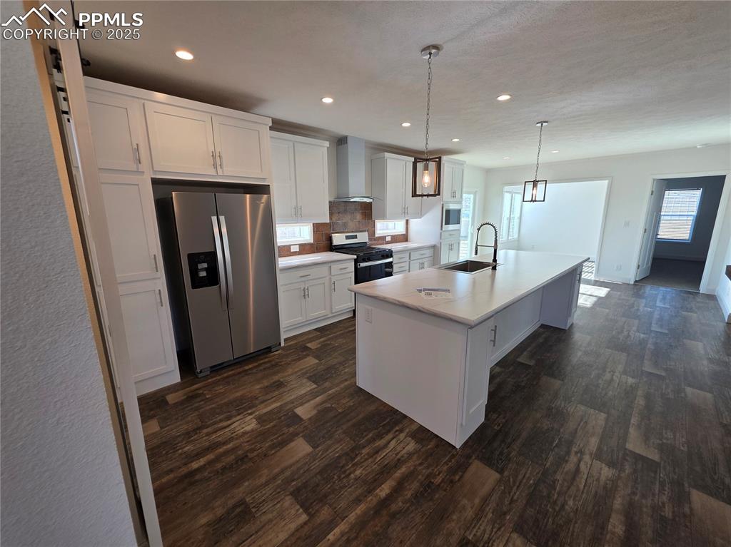 Image 9 of 25: Kitchen featuring white cabinets, stainless steel appliances, hanging light