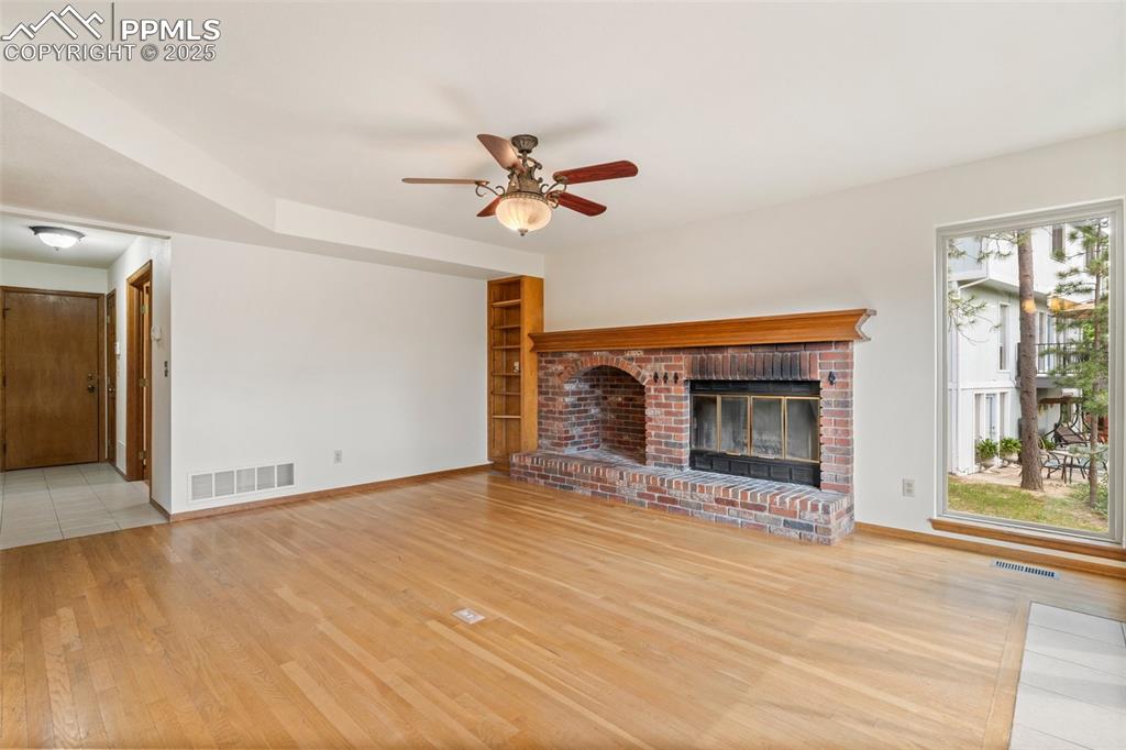 Image 11 of 26: Unfurnished living room featuring wood finished floors, ceiling fan, and a
