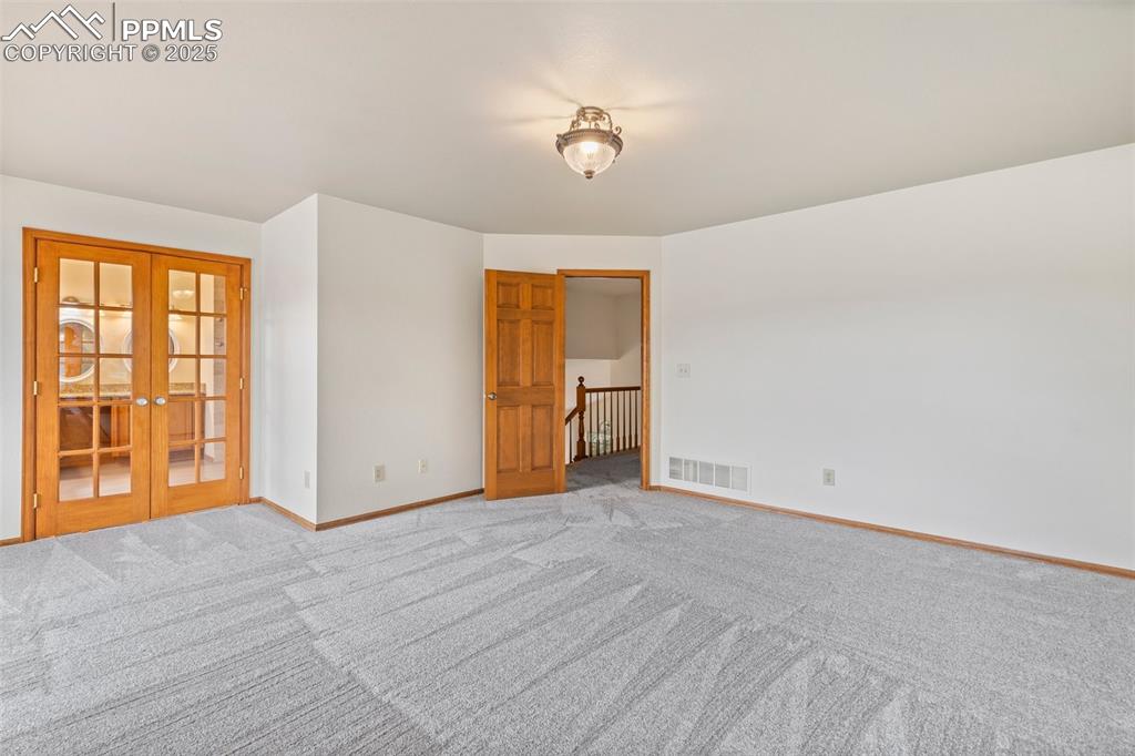 Image 15 of 26: Unfurnished room with french doors and light carpet