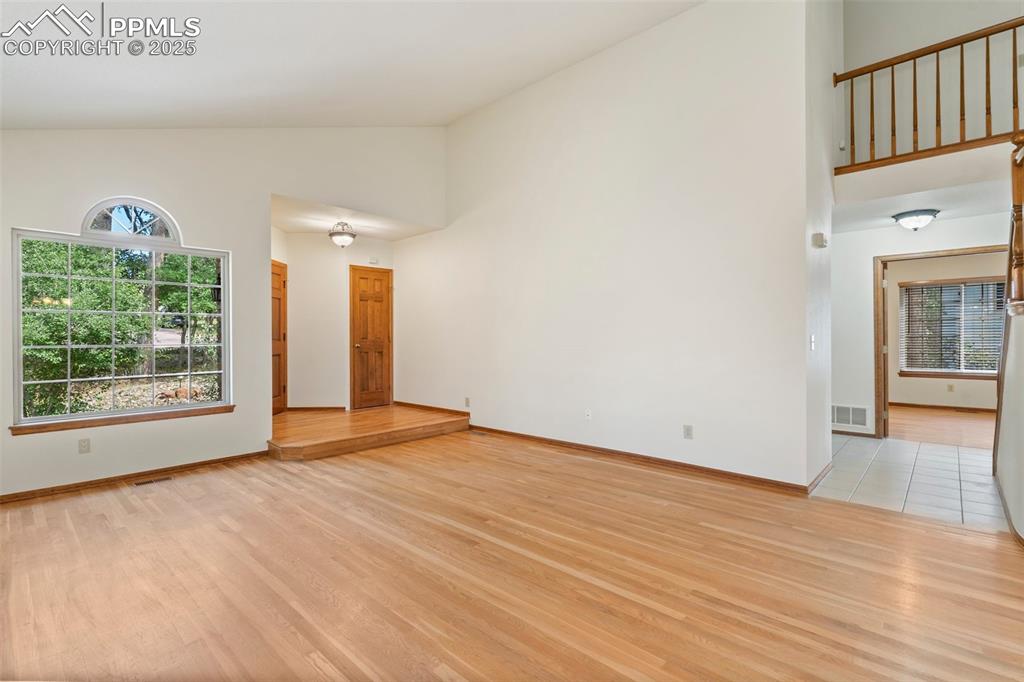 Image 4 of 26: Unfurnished room with high vaulted ceiling and light wood-style flooring