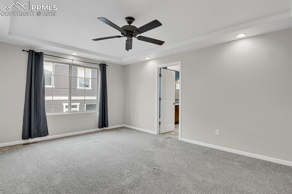 Image 17 of 30: Carpeted empty room with a tray ceiling, ceiling fan, and recessed lighting