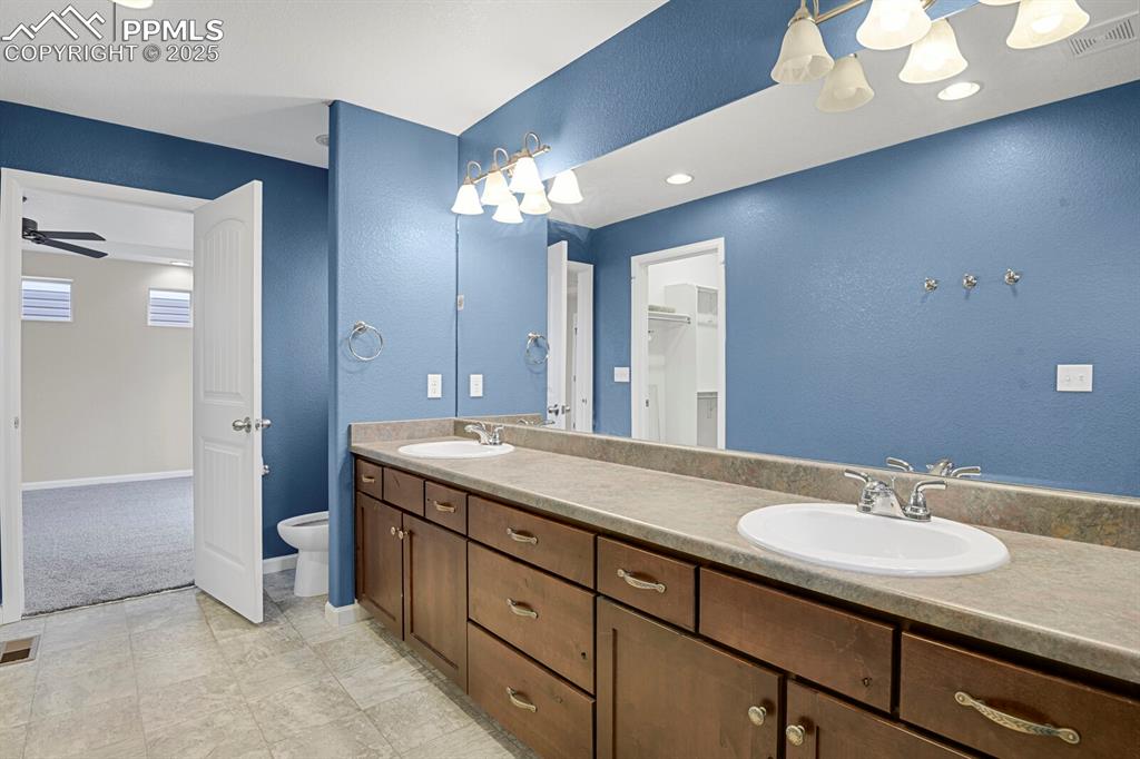 Image 19 of 30: Bathroom featuring a textured wall, double vanity, a walk in closet, a ceil