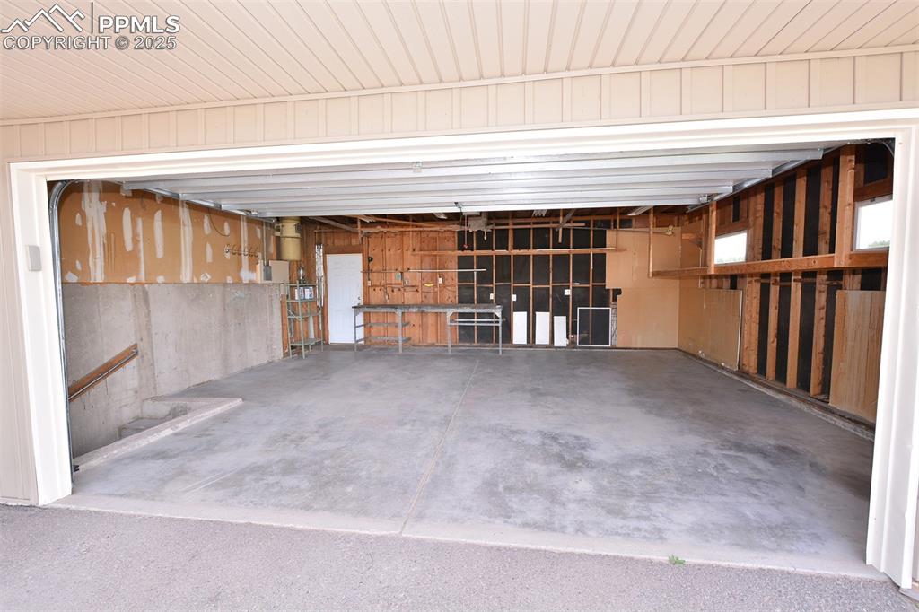 Image 43 of 50: Oversized garage with workbench and overhead storage