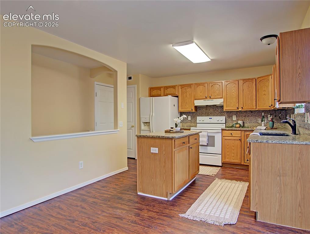 Image 10 of 28: Kitchen featuring wood-finish flooring, light wood cabinetry, white applian