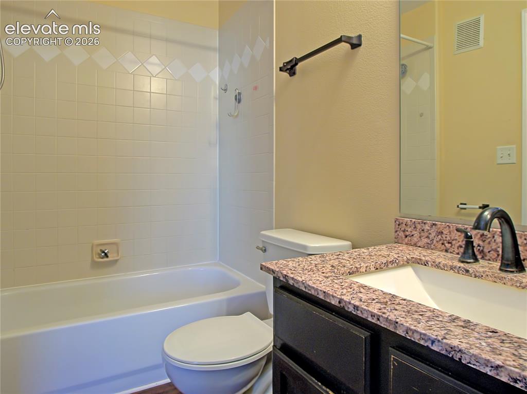 Image 14 of 28: Bathroom vanity featuring a speckled countertop, integrated sink, and dark