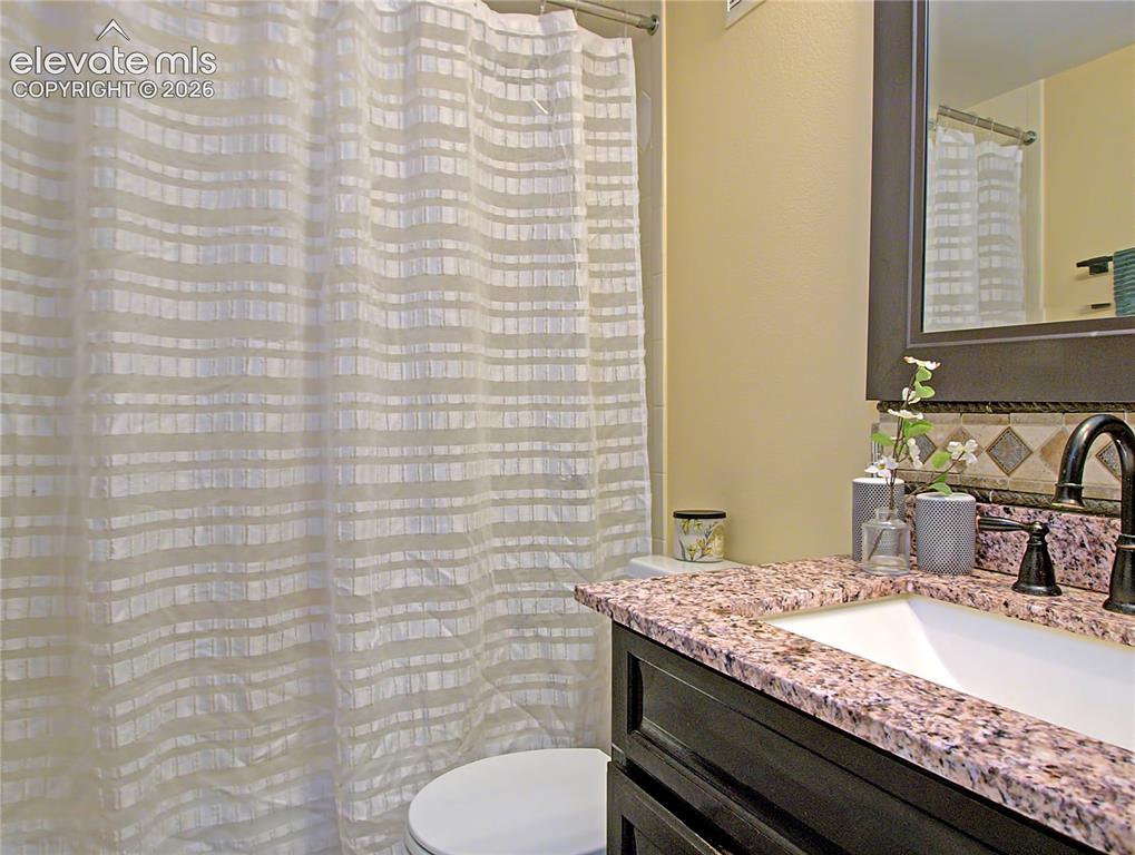 Image 16 of 28: Bathroom vanity featuring a speckled countertop, undermount sink, and dark