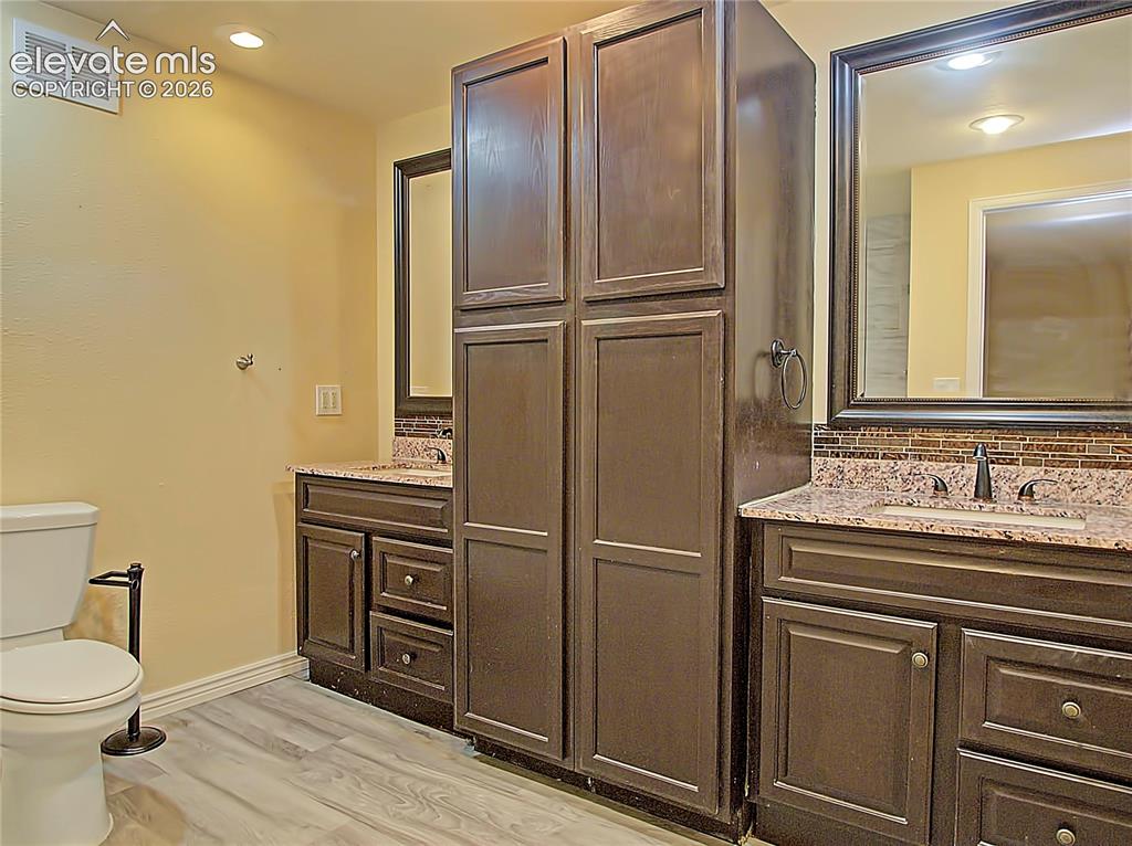 Image 22 of 28: Dual vanity with dark wood-finish cabinetry, granite countertops, decorativ