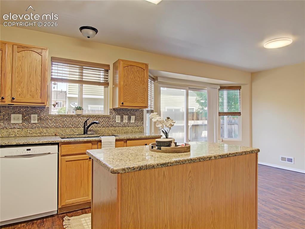 Image 7 of 28: Kitchen featuring wood cabinetry, light-toned countertops, tile backsplash,