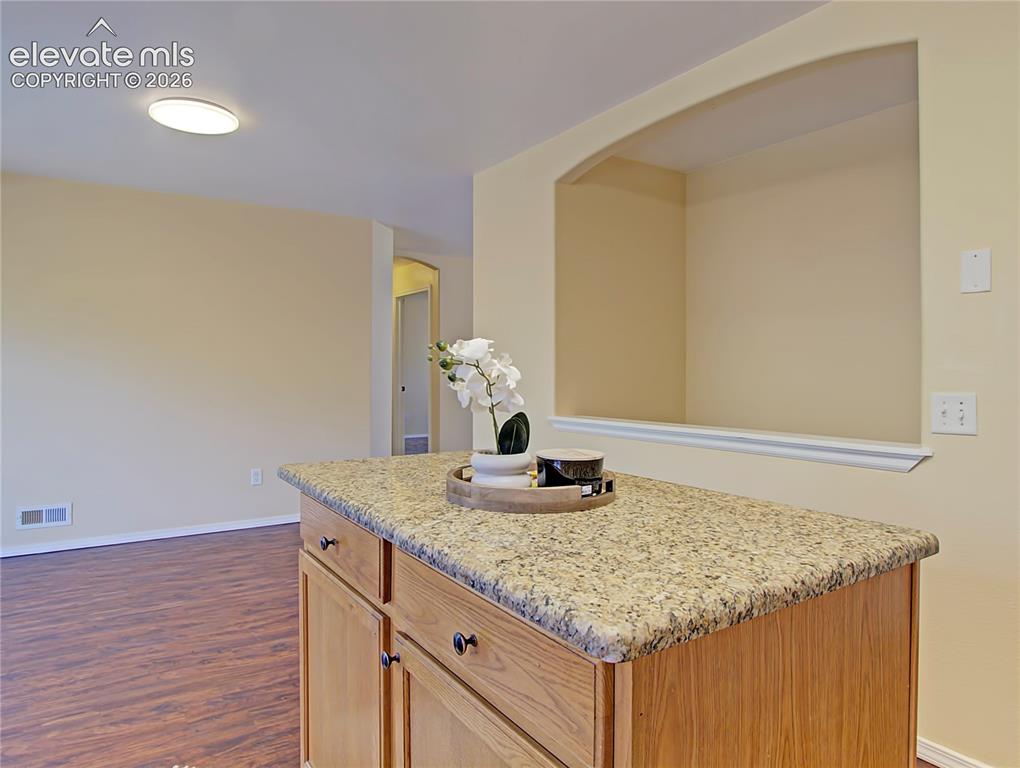 Image 9 of 28: Kitchen island with a speckled countertop, light wood-finish cabinetry, and