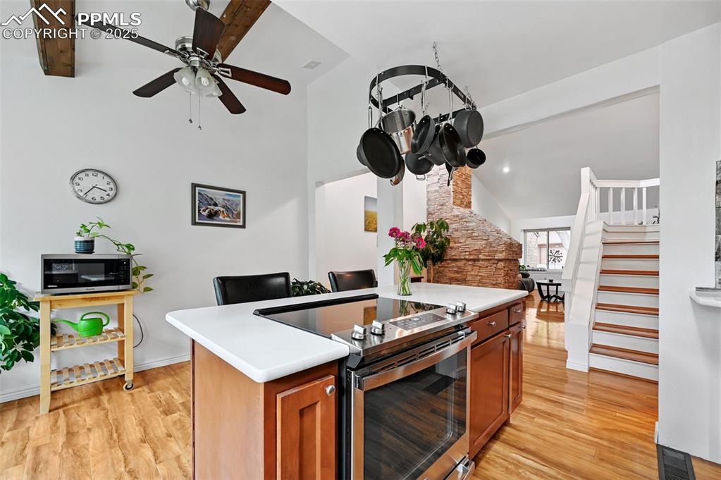 Image 9 of 42: Island with smooth top stove and easily accessible pot rack.