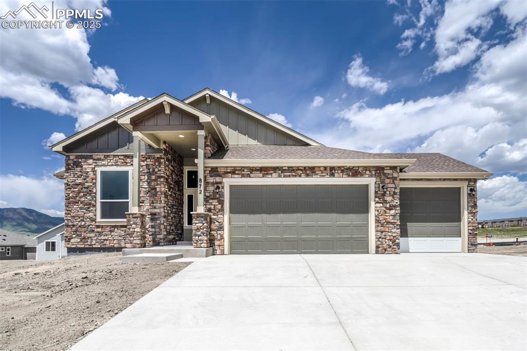 Caption: View of front featuring stone siding and a 3 car garage