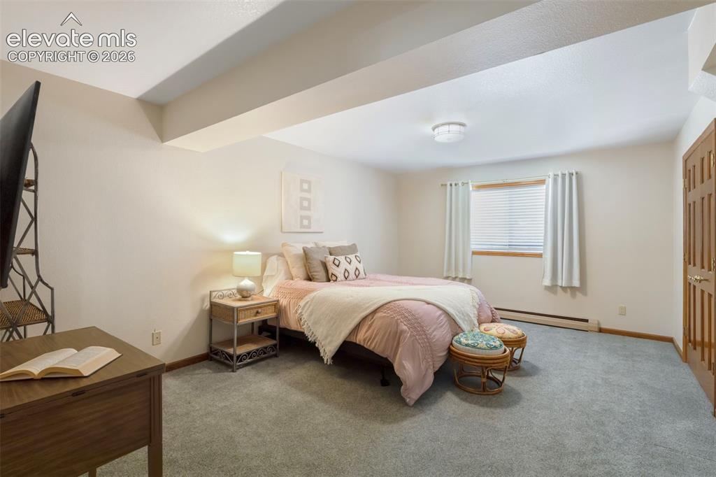 Image 39 of 46: Carpeted room with a full-lite window featuring blinds and drapes, a wood-f