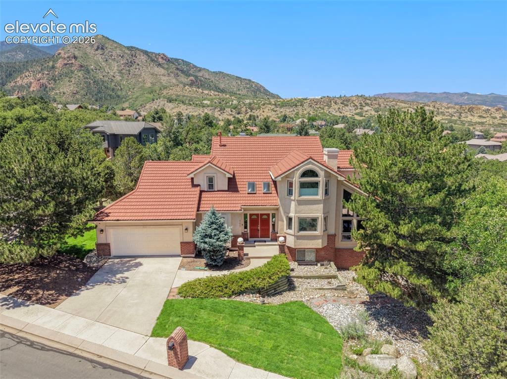 Image 4 of 46: Stucco exterior with a terracotta tile roof, prominent bay window, and a tw