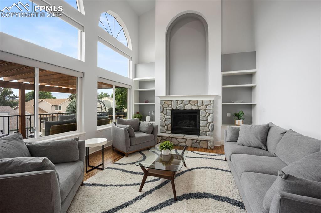 Image 12 of 44: Living room featuring wood finished floors, a towering ceiling, built in fe