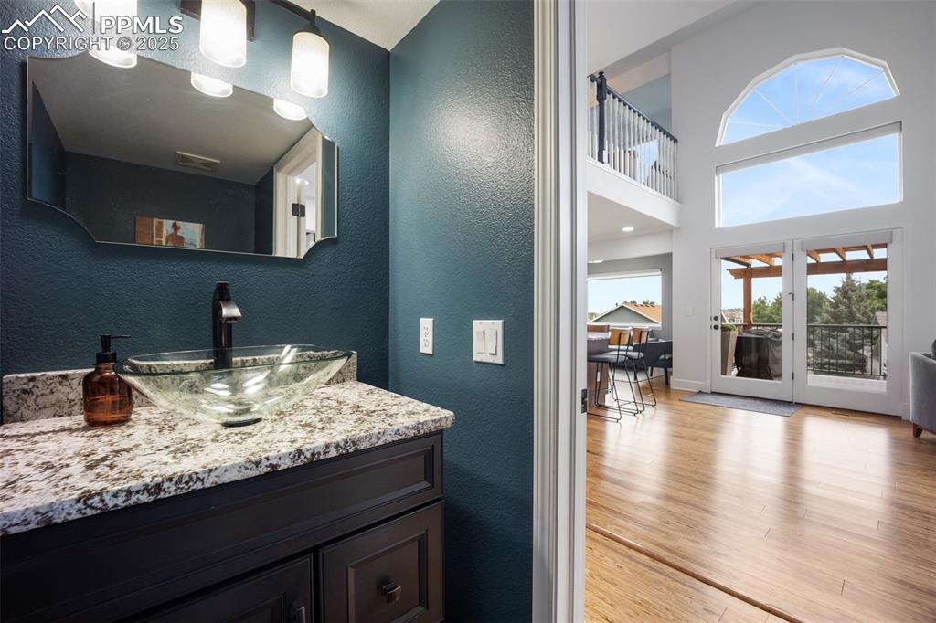 Image 13 of 44: Bathroom featuring a textured wall, wood finished floors, vanity, and a hig