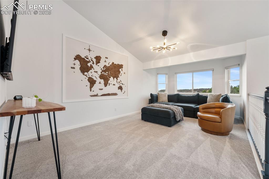 Image 19 of 44: Living area with carpet floors, vaulted ceiling, and a chandelier