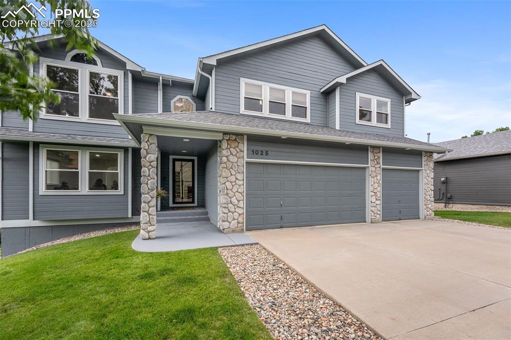 Image 2 of 44: View of front of home featuring an attached garage, concrete driveway, ston