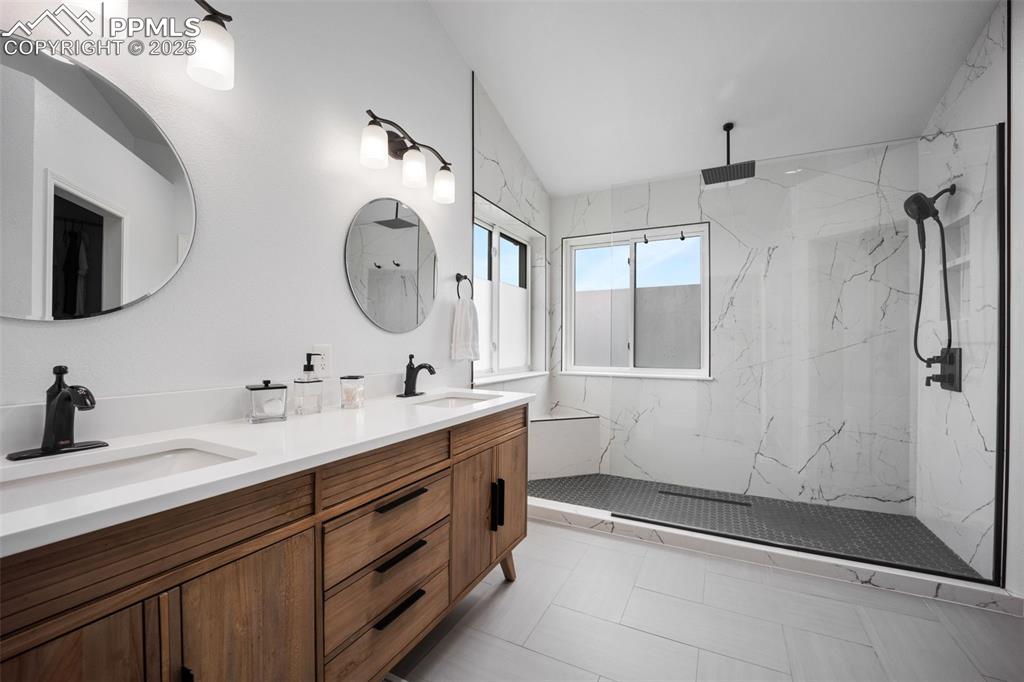 Image 23 of 44: Full bath with double vanity, a marble finish shower, vaulted ceiling, and