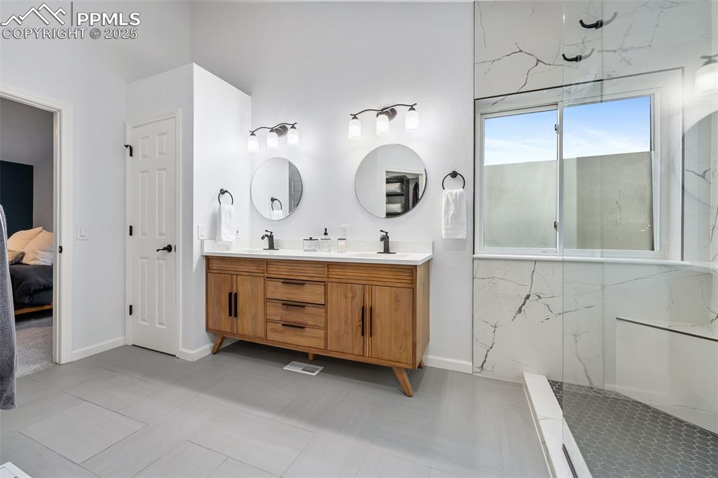 Image 25 of 44: Ensuite bathroom featuring double vanity and a marble finish shower