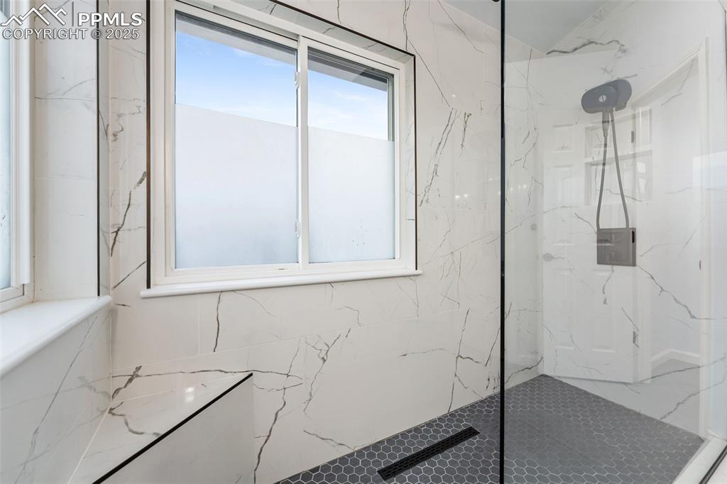 Image 26 of 44: Full bath with a marble finish shower