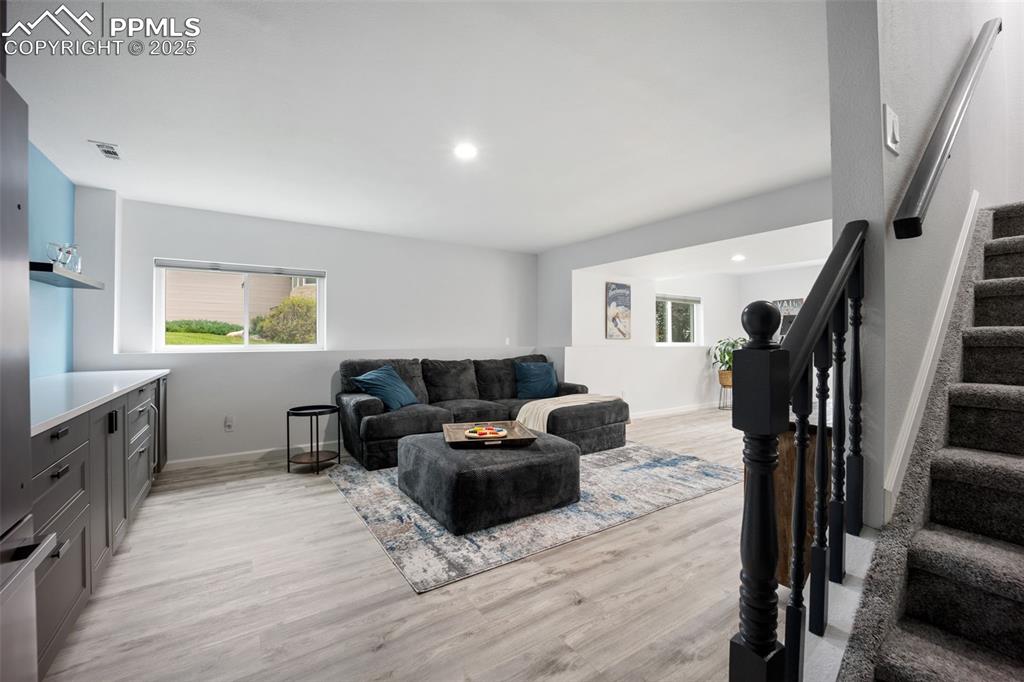 Image 27 of 44: Living area with light wood-style floors, stairway, and recessed lighting