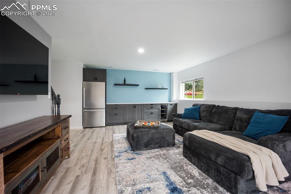Image 29 of 44: Living area with light wood finished floors and recessed lighting