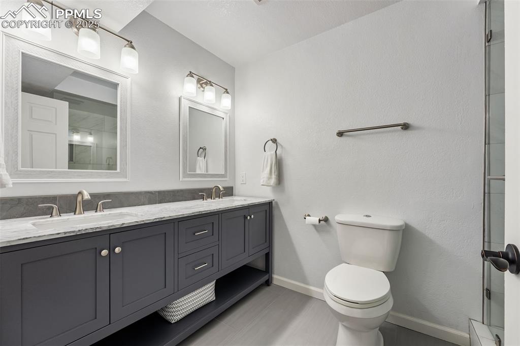 Image 33 of 44: Bathroom featuring double vanity, a shower, and a textured wall
