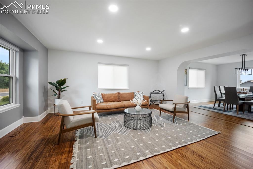 Image 4 of 44: Living room with arched walkways, wood finished floors, plenty of natural l