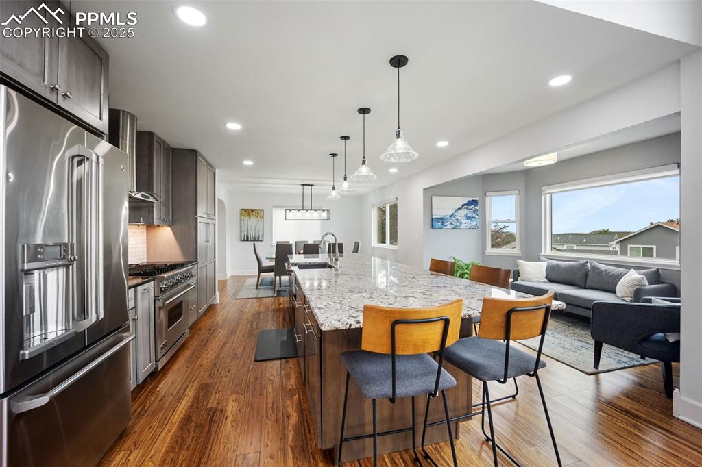 Image 7 of 44: Kitchen featuring premium appliances, dark wood-style flooring, a large isl