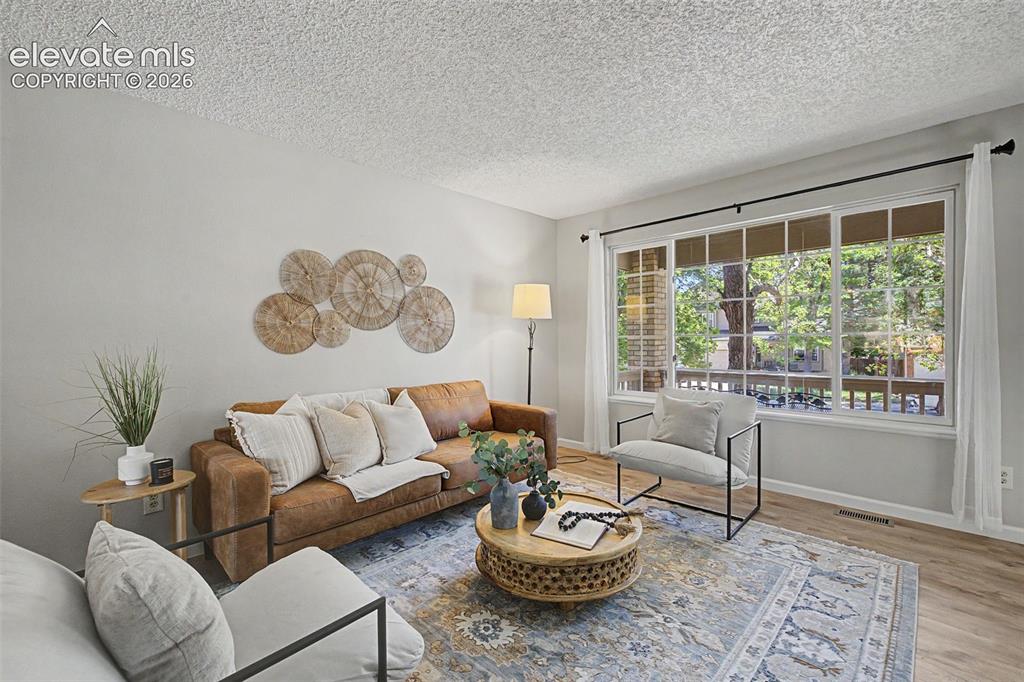Image 10 of 49: Bright living area featuring a large picture window, neutral wall paint, an