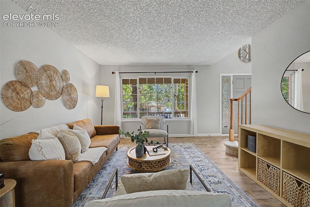 Image 11 of 49: Living space featuring wood-finish flooring, a large window with white trim
