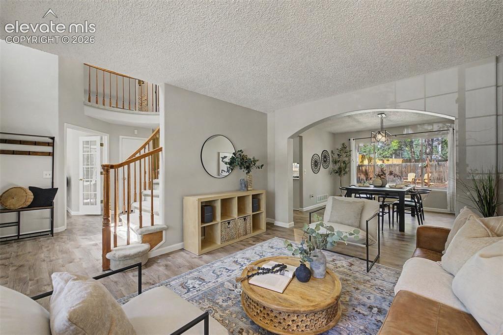 Image 13 of 49: Open-concept living area with wood-finish flooring, a two-story entryway, a